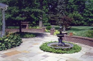 Bluestone rear patio with brick seat wells, fireplace & iron fountain.