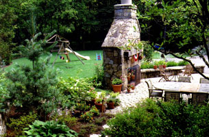 Outdoor fireplace "divides" dining and play areas on large wooded lot.