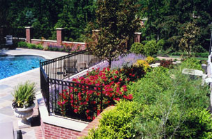 Brick walls and iron fencing add structure to multi-level pool garden.