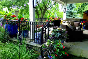 Wrought iron fencing, a rooftop bluestone entertainment area,  and a beautiful fireplace are complemented with harmonious ceramic urns filled with large tropicals and long blooming annuals especially for hummingbirds, pollinating bees and butterflies, as well as strategic privacy.